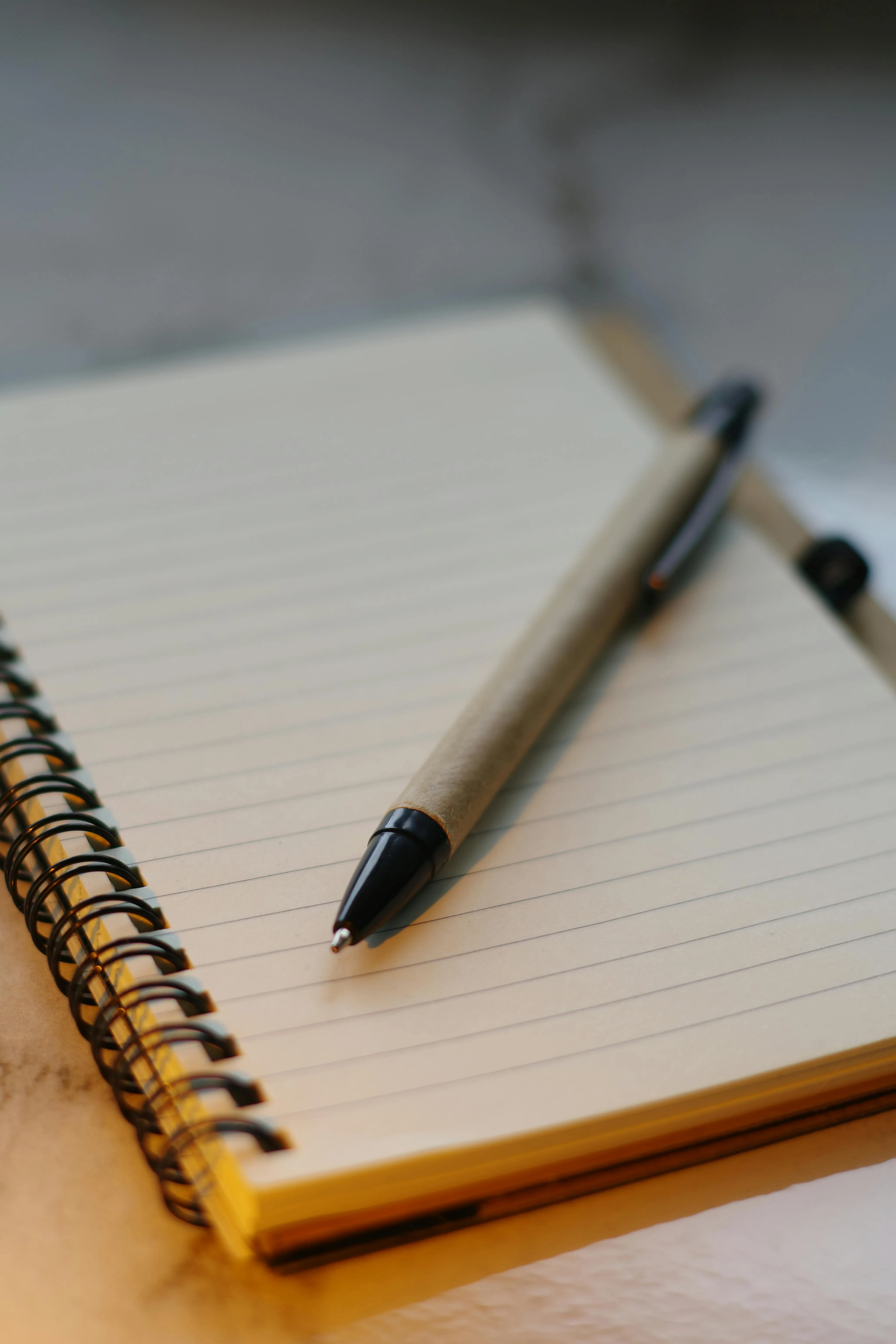 A pen on top of a notebook with blank paper
